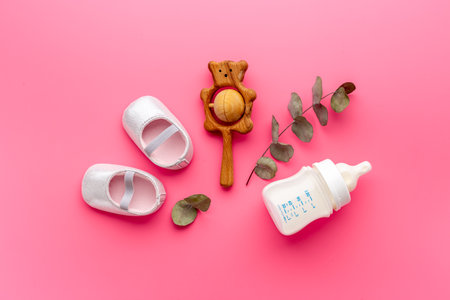 Baby newborn pink booties with bootle of milk and wooden toyの写真素材