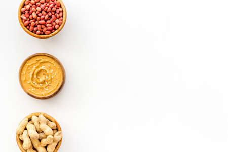 Creamy peanut butter and nuts in wooden bowls, top view
