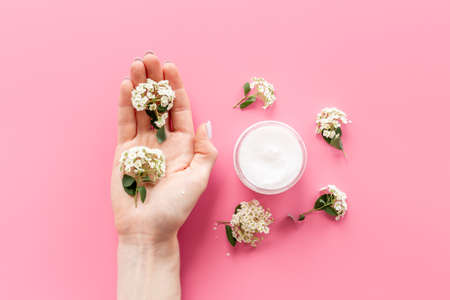 Hand holds herbal cream cosmetic for skin care with white flowersの写真素材
