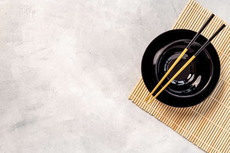 Black bowl with golden chopsticks for Asian table place setting.の写真素材