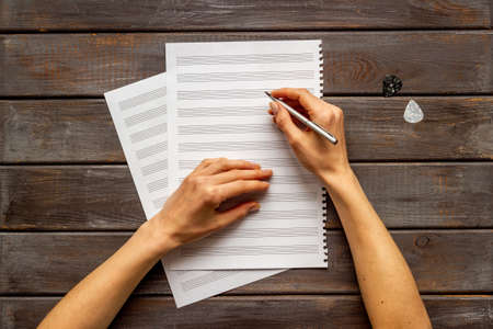 Music sheets with hands writing notes. Compose music concept