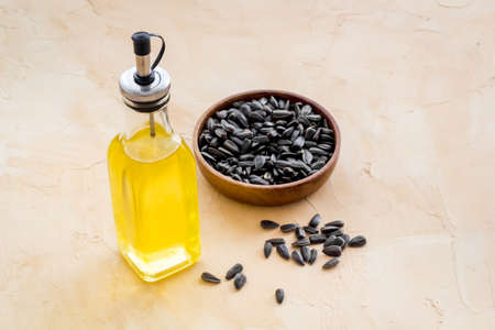Bottle of sunflower cooking oil with seeds in bowlの写真素材