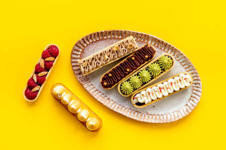 A lot of french dessert eclairs with colorful topping