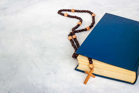 Old Bible book and rosary beads with cross. Christian religion concept