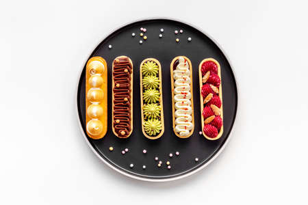 A lot of french dessert eclairs with colorful toppingの写真素材