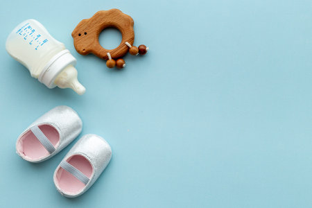 Baby newborn pink booties with bottle of milk and wooden toyの写真素材