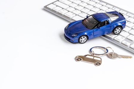 Buy or rent a car concept. Toy car near computer keyboardの写真素材