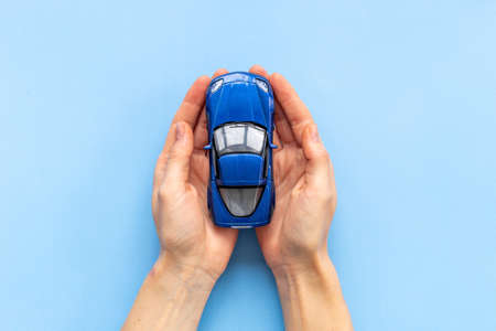Car insurance or driving safety concept. Toy car in handsの写真素材