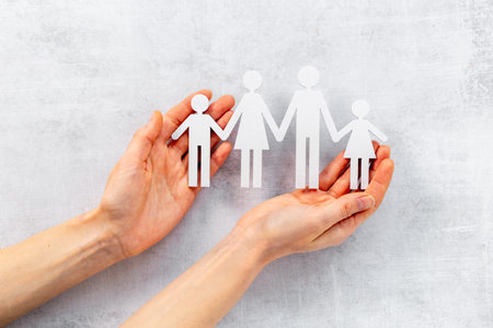 Hands holding wooden figures of family. Care and protection concept