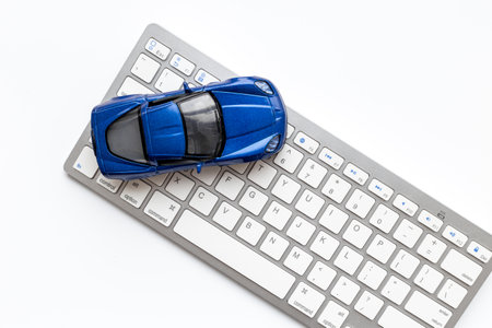 Buy or rent a car concept. Toy car near computer keyboardの写真素材