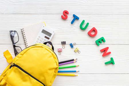 Yellow school backpack with colorful school stationery