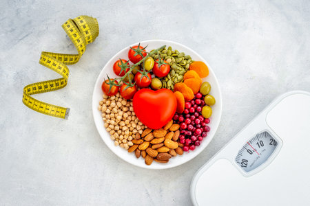 Fat control diet. Healthy food in heart shaped plate with weight scaleの写真素材