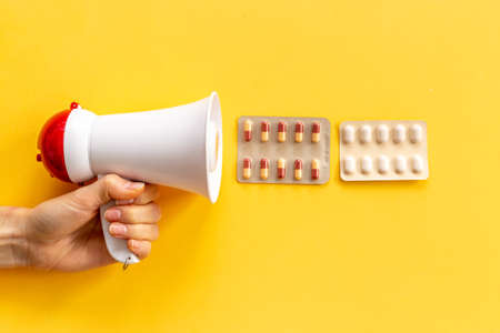 Megaphone wirh flying out pills. Medical treatment concept