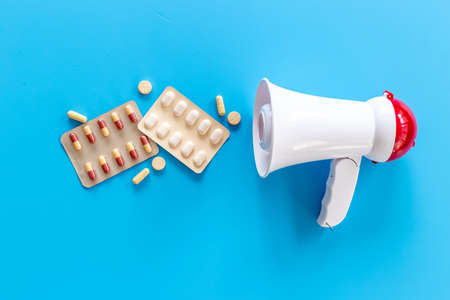 Health care and medical treatment concept with megaphone and pills