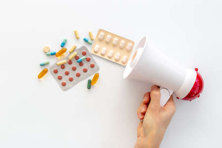 Health care and medical treatment concept with megaphone and pillsの写真素材