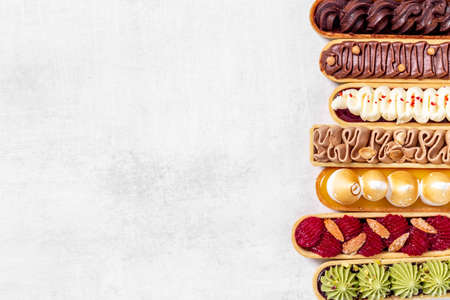 A lot of french dessert eclairs with colorful toppingの写真素材