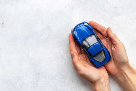 Car insurance concept. Toy car in hands, top viewの写真素材