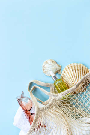 Summer background with sunglasses and beach shoes in grid string bagの写真素材