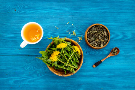 Yellow meadow dandelions with tea and dry leaves in bowl, top viewの写真素材