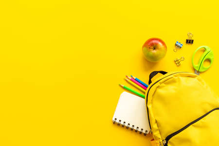 Layout of yellow school backpack full of stationery with appleの写真素材