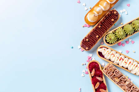 A lot of french dessert eclairs with colorful topping