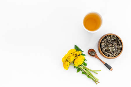 Yellow meadow dandelions with tea and dry leaves in bowl, top viewの写真素材