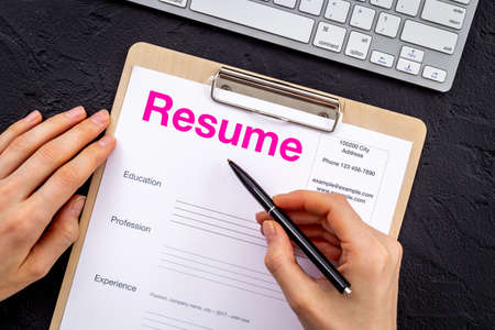 Hands with resume application form on office table. Find new job concept