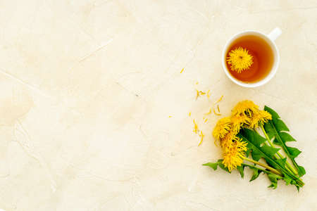 Cup of healing herbal tea with yellow dandelions blossoms and leavesの写真素材