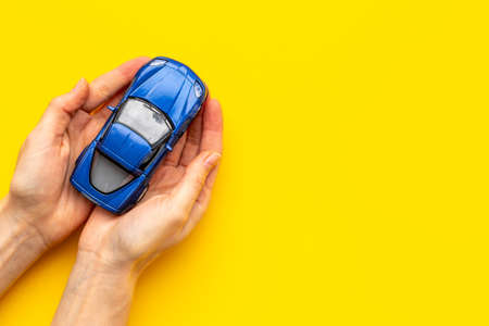 Car insurance concept. Toy car in hands, top viewの写真素材