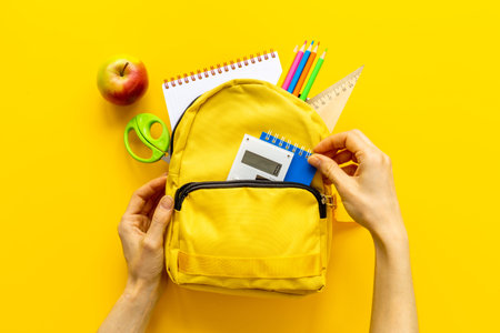 Layout of yellow school backpack full of stationery with appleの写真素材