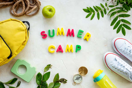 Summer camping background with backpack sneakers green tree branchesの写真素材