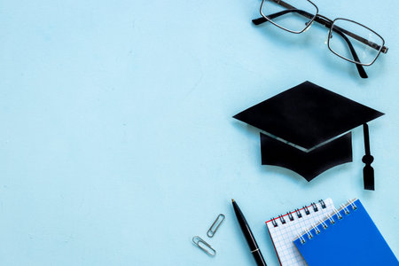 Black academic cap or graduation hat on students table, top viewの写真素材