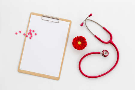 White blank of doctor gynecologist clipboard with red flower and stethoscopeの写真素材