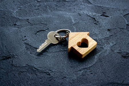 Wooden house shaped keychain with keys. Real estate concept