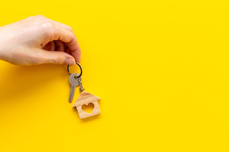 House shaped keychain and keys in hand. Sale or rent real estate concept