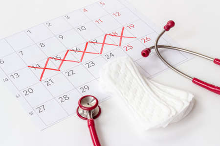 Women health. Stethoscope and calendar with red days of menstruation periodの写真素材