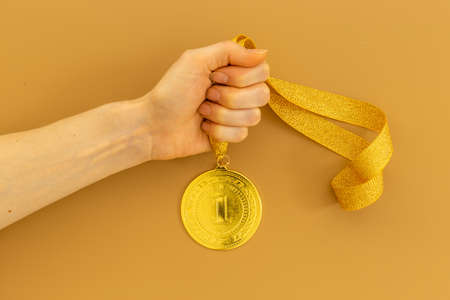 Hand holding gold medal first place. Winner of competition conceptの写真素材