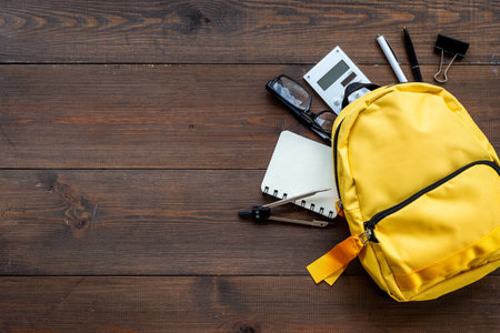 Classic yellow school backpack top view. Educational objects background