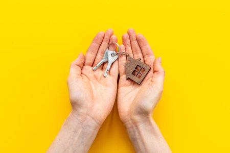 Hands holding house shaped keychain and keys. Real estate concept