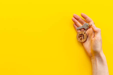 House shaped key chain and keys in hand. Sale or rent real estate conceptの写真素材