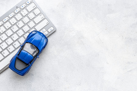 Buy or rent a car concept. Toy car near computer keyboard