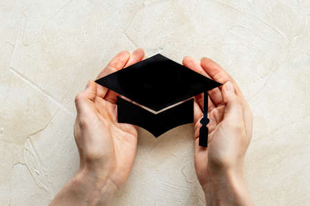 Hands holding graduation hat or academic cap paper cut. Education conceptの写真素材