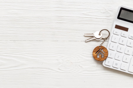 Saving money for buy house concept. House shaped key chain with calculatorの写真素材