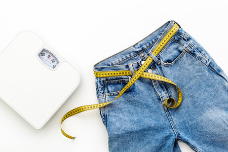 Weight loss concept with jeans with measuring tape belt and scalesの写真素材