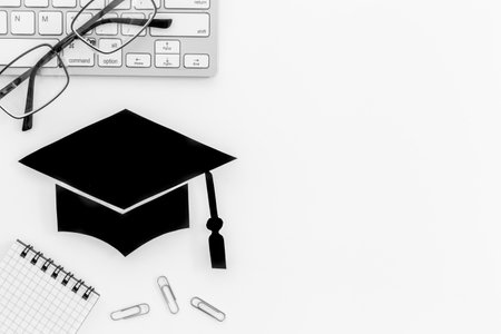 Black academic cap or graduation hat on students table, top viewの写真素材