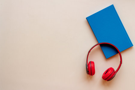 Audiobook concept - book and headphones nearby. Flat lay, top view