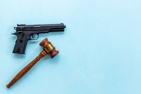 Gun law concept. Hand gun weapon and judges gavel. Crime backgroundの写真素材