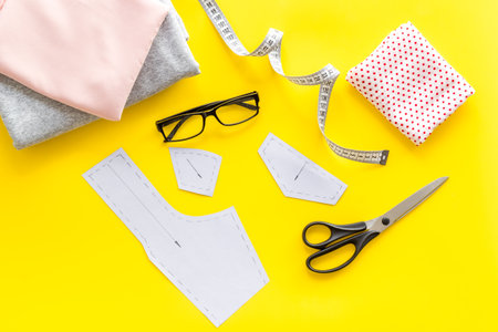 Tailors workplace with sewing patterns and cotton dress fabric, top view.