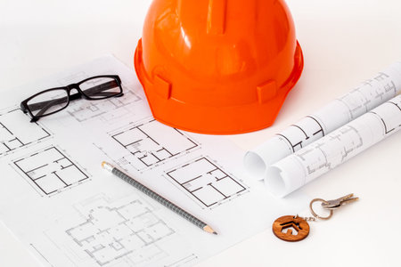 Construction helmet on drawing blueprints for house design and architect plan.