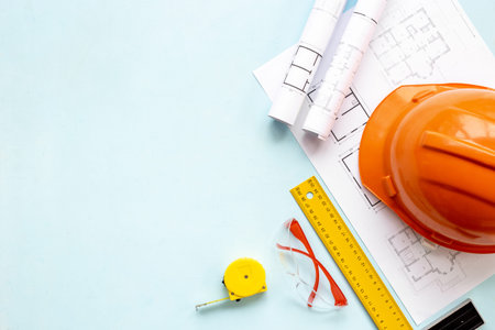Top view of construction helmet on drawing blueprints for house design and architect plan.